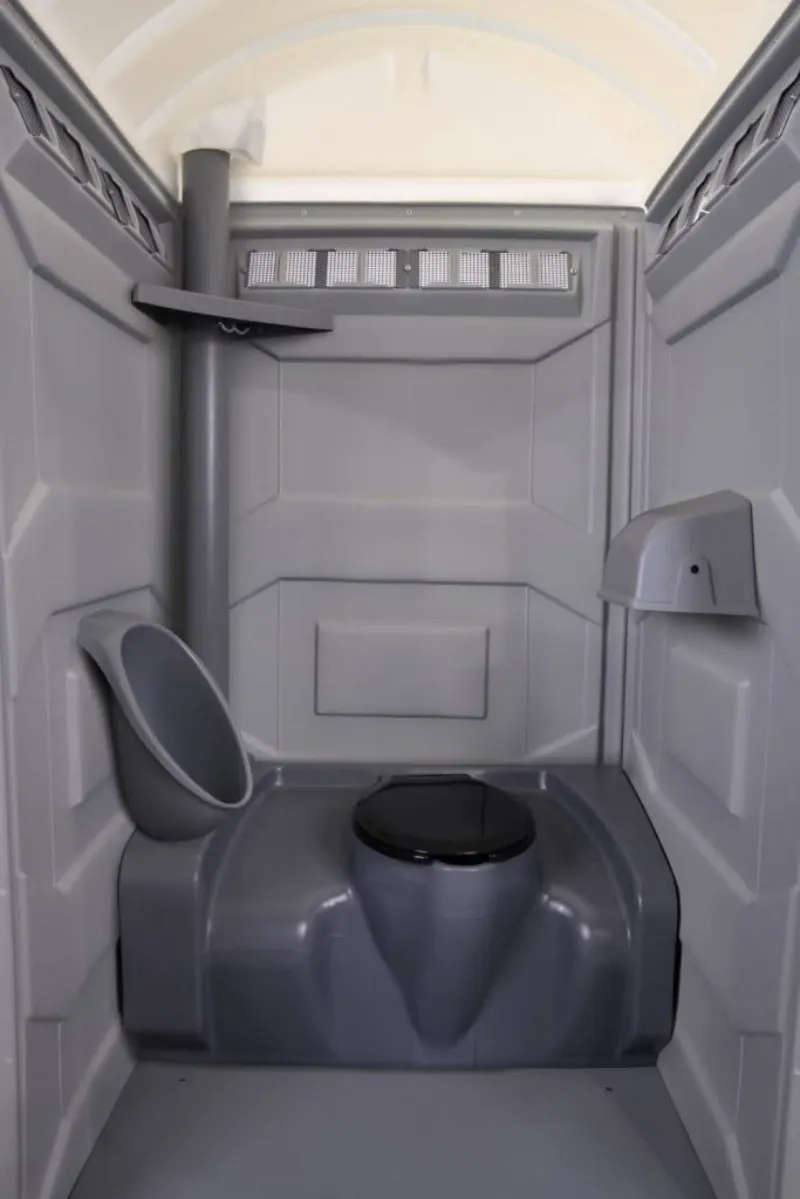 Inside a porta potty with a toilet seat, urinal, and vent, available for construction site rental in Rochester, NY