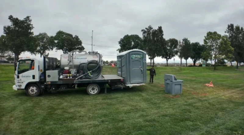Service truck delivering a porta potty and hand wash station to a park in Rochester