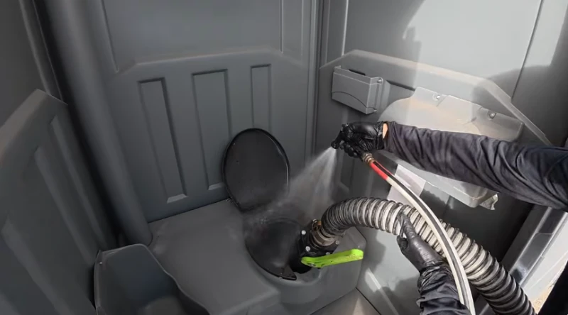 Technician cleaning and servicing the inside of a portable toilet