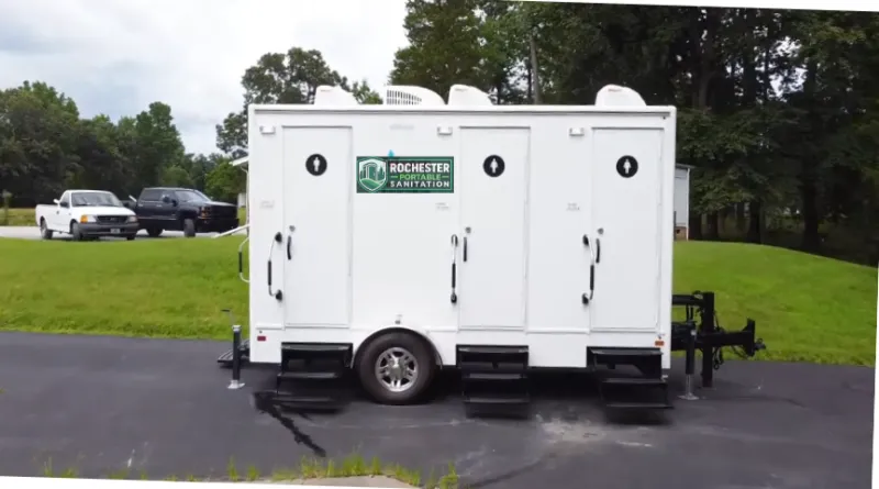 White Rochester Portable Sanitation restroom trailer with three doors parked on pavement in Rochester, NY