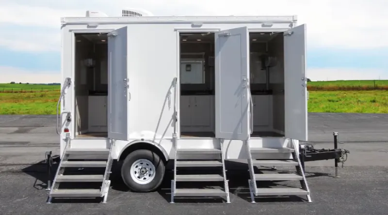 Side view of a white three-door restroom trailer with all doors open and steps down, available for rental in Rochester, NY